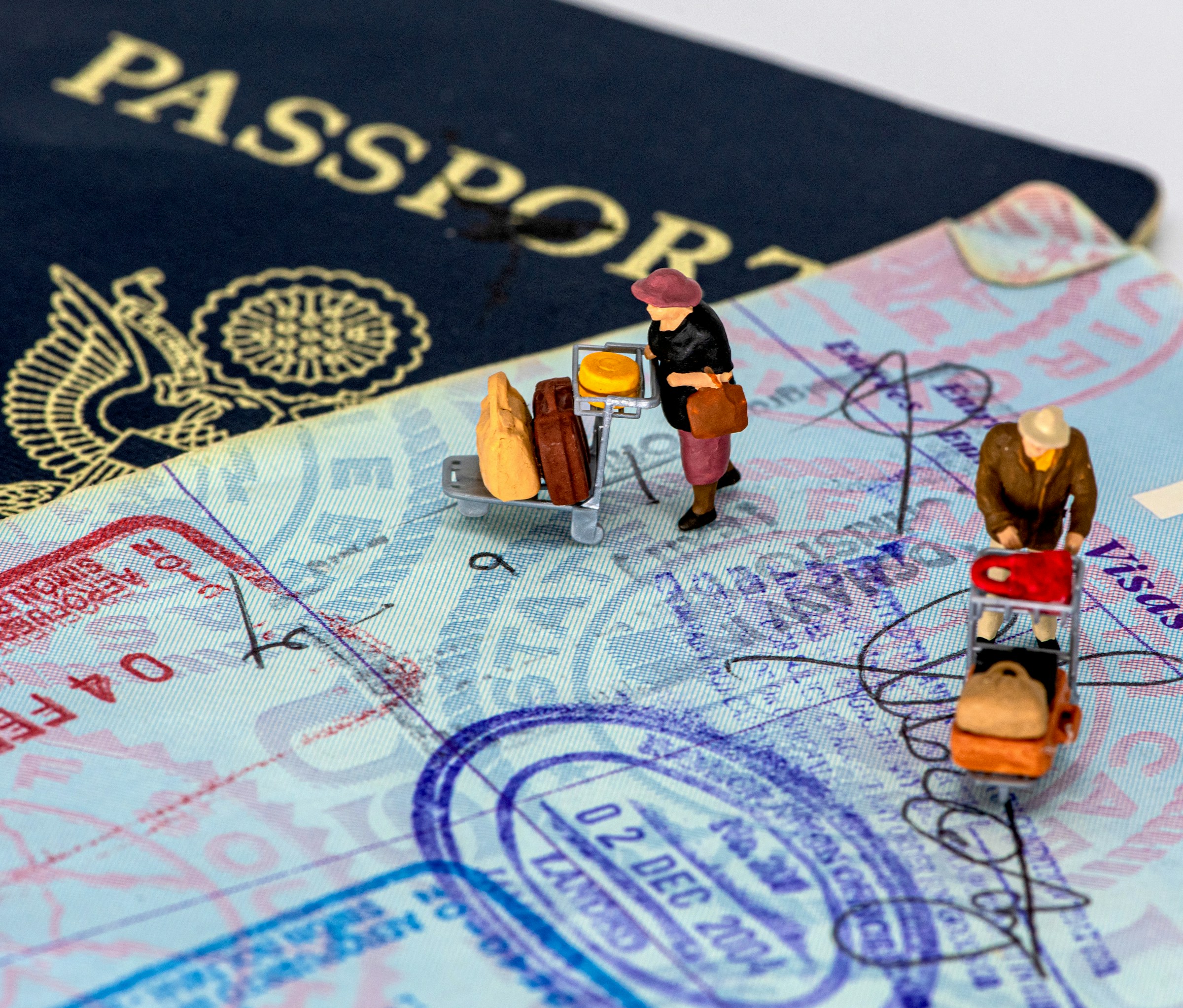Open US passports with toy travelers